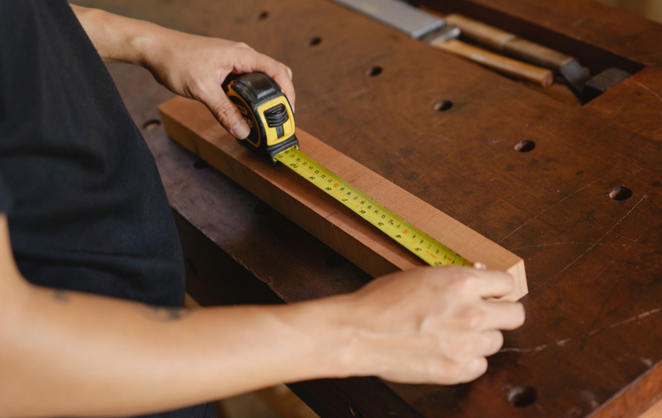 Tischler misst Holz in einer Werkstatt für einen individuellen Kundenauftrag aus