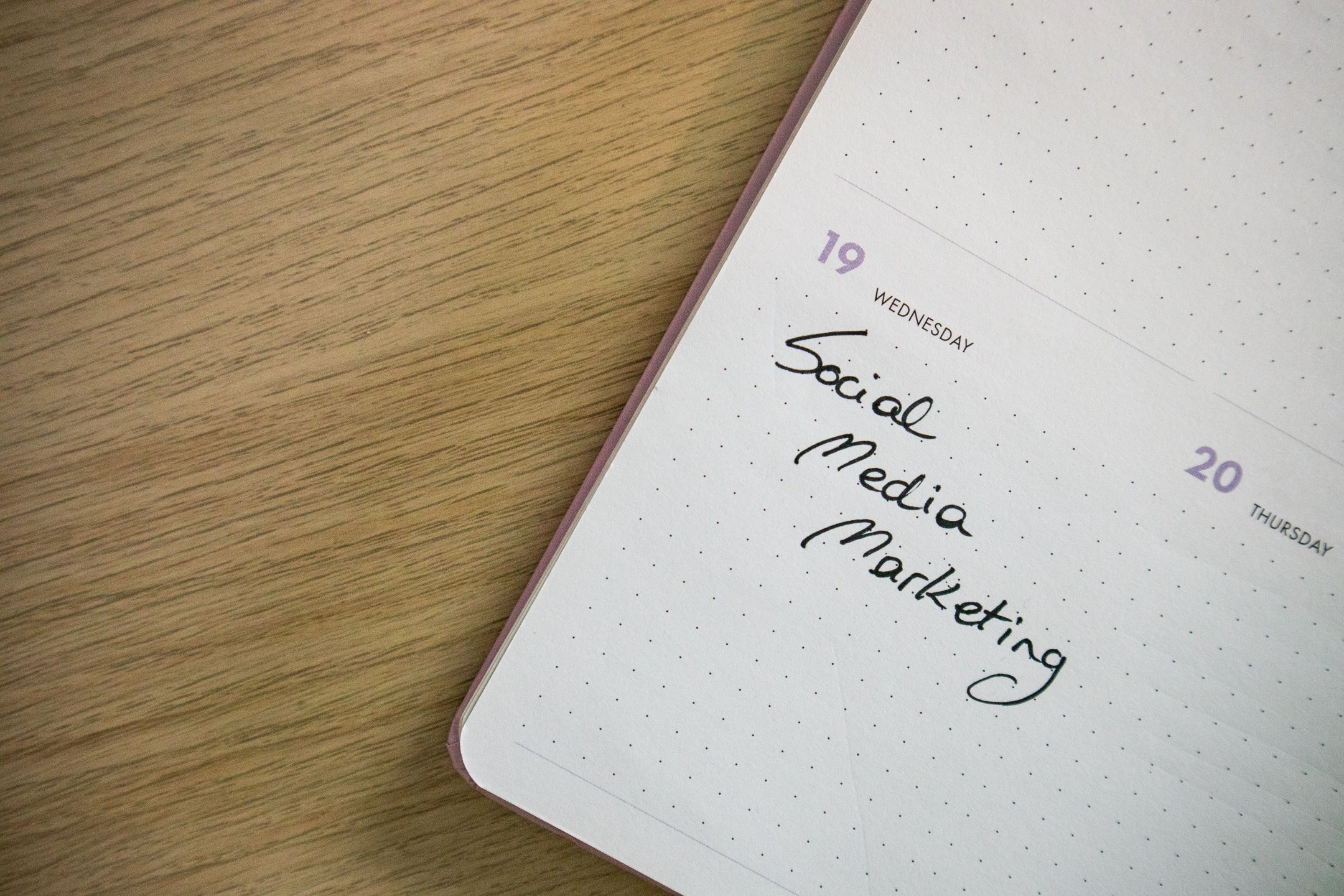 Social Media Manager plant Inhalte mit Smartphone und Notizen