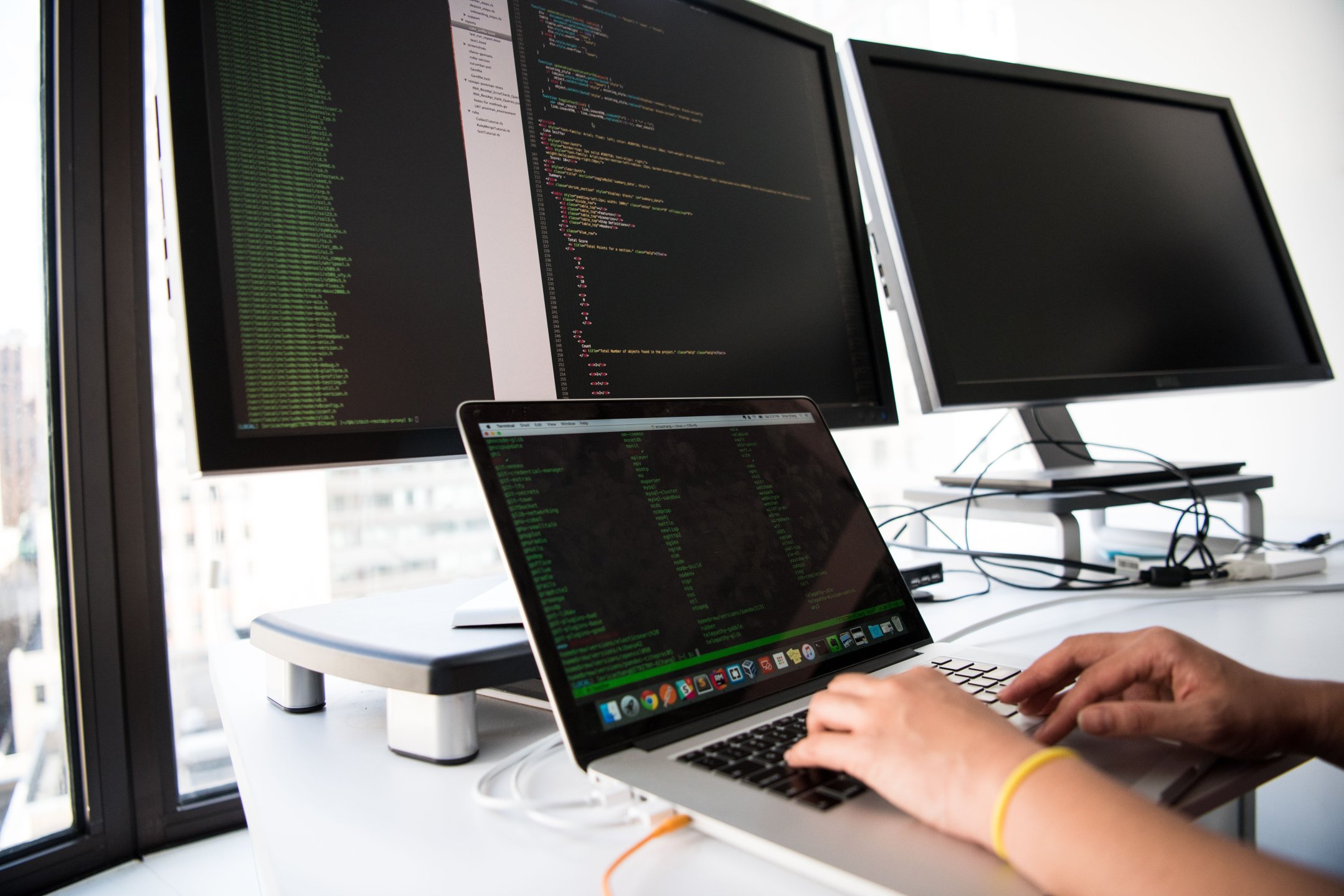Softwareentwickler arbeitet an Code auf mehreren Bildschirmen